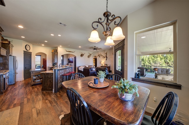 dining space with dark hardwood / wood-style floors and ceiling fan with notable chandelier