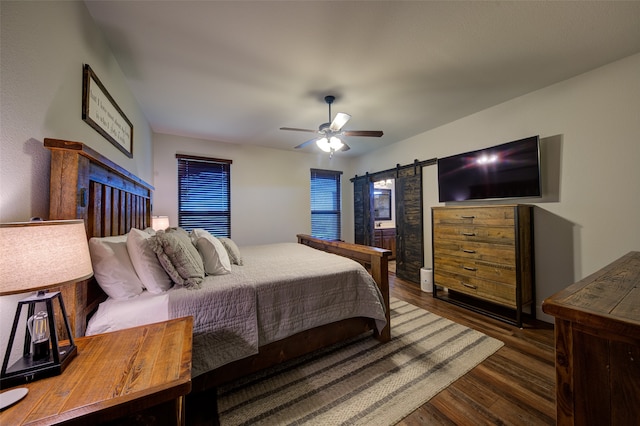 bedroom with dark hardwood / wood-style flooring, ceiling fan, and a barn door