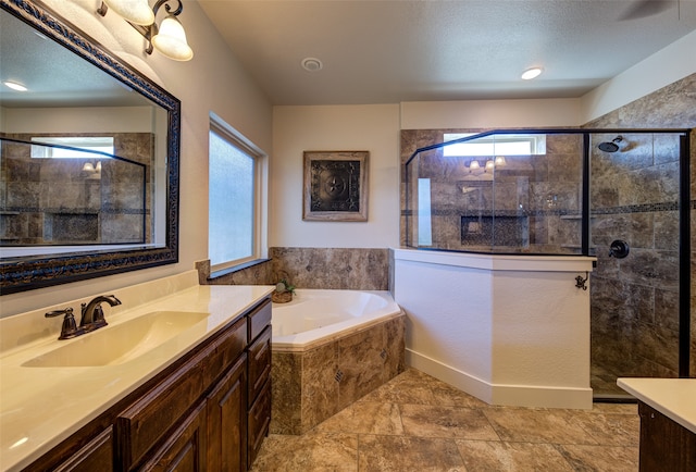 bathroom featuring plenty of natural light, independent shower and bath, a textured ceiling, and vanity