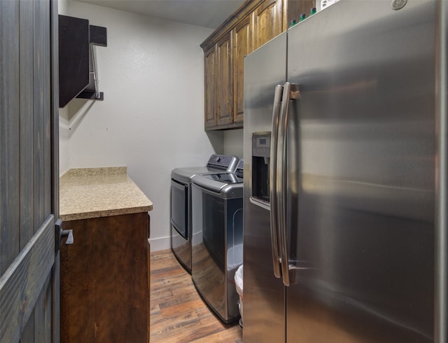 laundry room featuring hardwood / wood-style flooring, washing machine and dryer, and cabinets