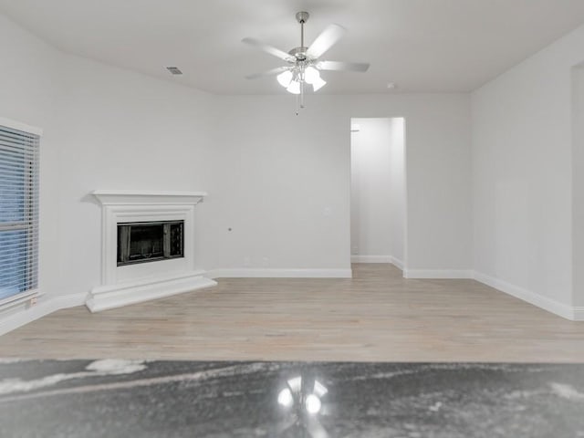 unfurnished living room with light hardwood / wood-style flooring and ceiling fan