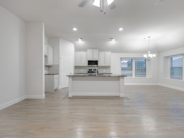 kitchen featuring sink, light hardwood / wood-style floors, an island with sink, and white cabinets