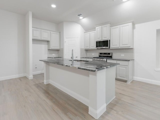 kitchen with stainless steel appliances, sink, dark stone countertops, and white cabinets