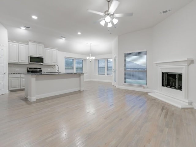 kitchen featuring white cabinetry, appliances with stainless steel finishes, a center island with sink, and pendant lighting