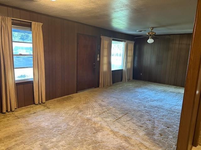 6371 Buncombe Rd, Shreveport, LA 71129 - carpeted spare room with wooden walls, ceiling fan, and a textured ceiling