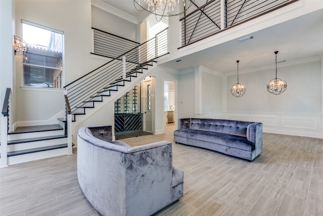 living room featuring an inviting chandelier, ornamental molding, and light wood-type flooring