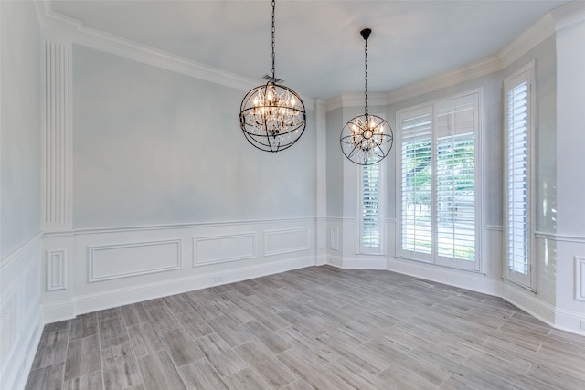 spare room with light hardwood / wood-style flooring, an inviting chandelier, and ornamental molding