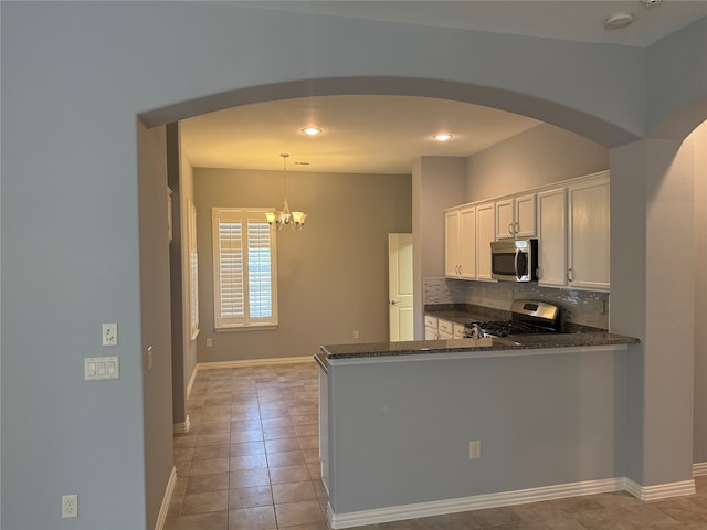 kitchen with kitchen peninsula, pendant lighting, white cabinetry, appliances with stainless steel finishes, and tasteful backsplash