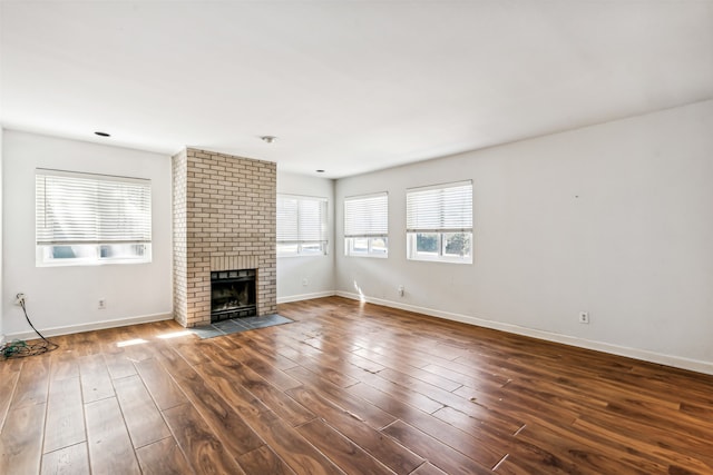 unfurnished living room featuring a brick fireplace and dark hardwood / wood-style floors