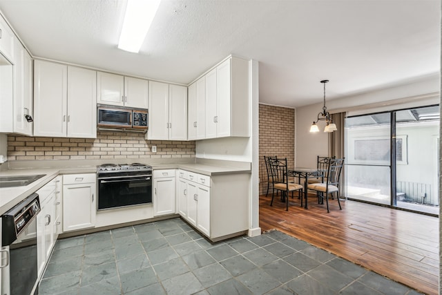 kitchen featuring black microwave, wood-type flooring, decorative light fixtures, stove, and white cabinetry