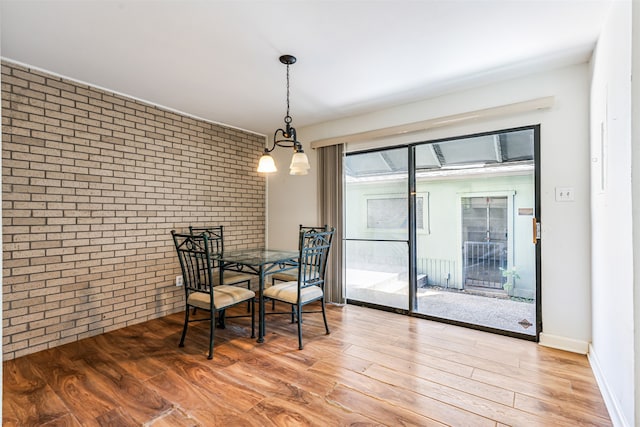 dining room with brick wall and wood-type flooring