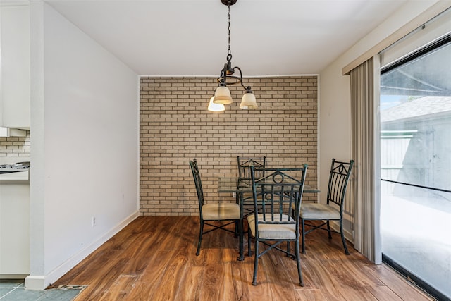 dining room with dark wood-type flooring and brick wall