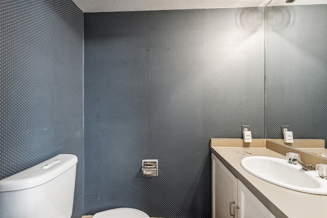 bathroom featuring vanity, toilet, and a textured ceiling