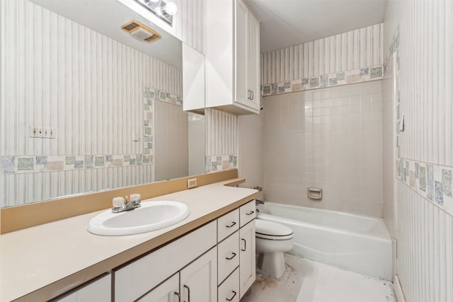 full bathroom with tiled shower / bath, vanity, and toilet