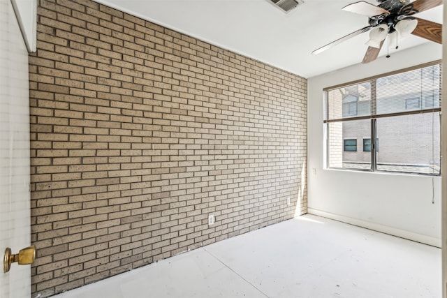 unfurnished room featuring ceiling fan, brick wall, and concrete flooring