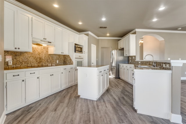 kitchen featuring kitchen peninsula, white cabinets, appliances with stainless steel finishes, light wood-type flooring, and sink