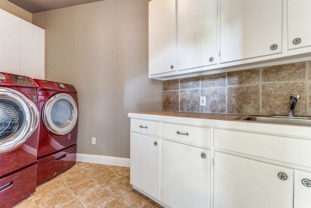 clothes washing area with cabinets, sink, separate washer and dryer, and light tile patterned floors