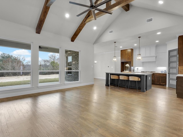 unfurnished living room with beamed ceiling, ceiling fan, wood-type flooring, and high vaulted ceiling