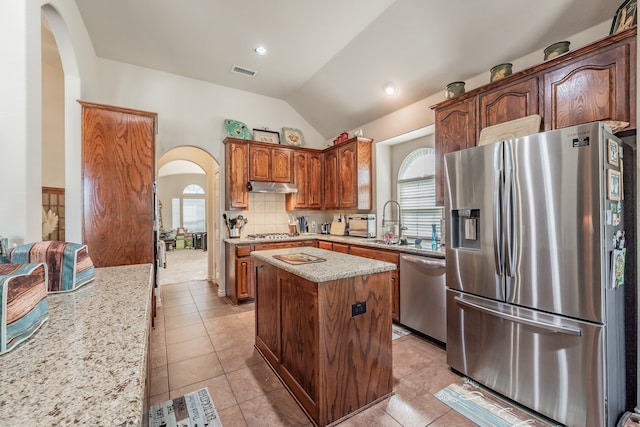 kitchen with appliances with stainless steel finishes, lofted ceiling, a healthy amount of sunlight, and a center island