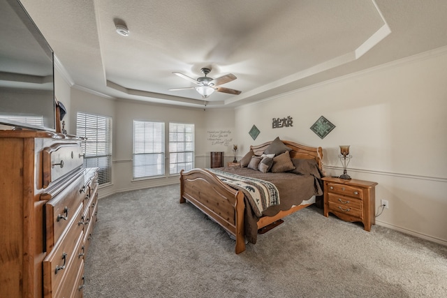 carpeted bedroom with ceiling fan, a raised ceiling, a textured ceiling, and crown molding