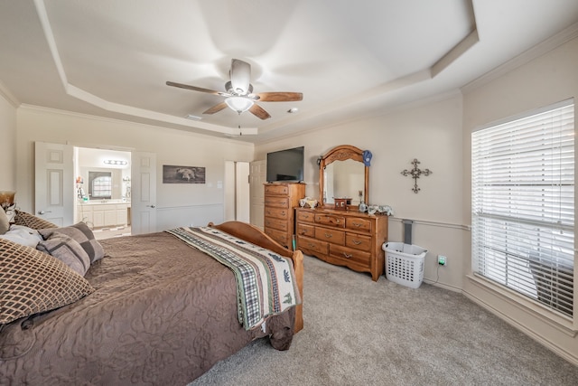 carpeted bedroom with crown molding, ensuite bath, a raised ceiling, and ceiling fan