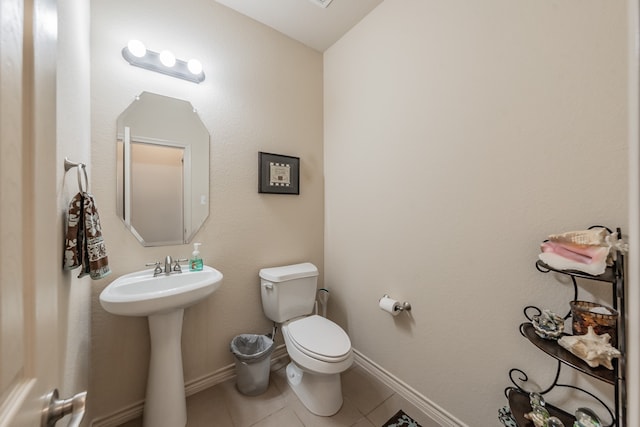 bathroom with toilet, sink, and tile patterned floors