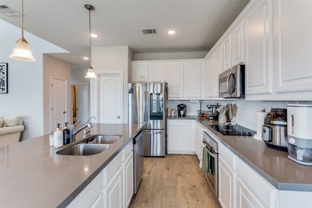 kitchen featuring white cabinets, stainless steel appliances, sink, and decorative light fixtures