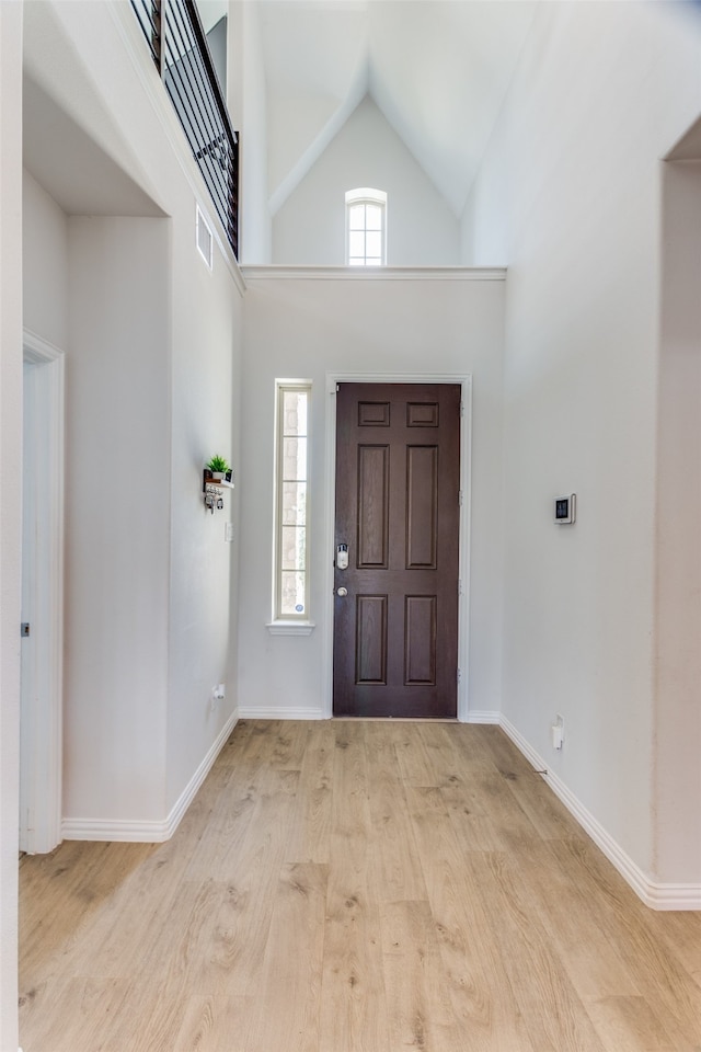 entrance foyer with high vaulted ceiling and light hardwood / wood-style floors