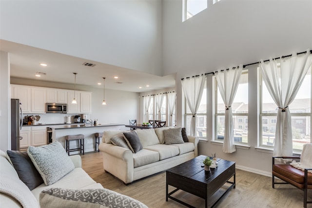 living room featuring a towering ceiling and light wood-type flooring