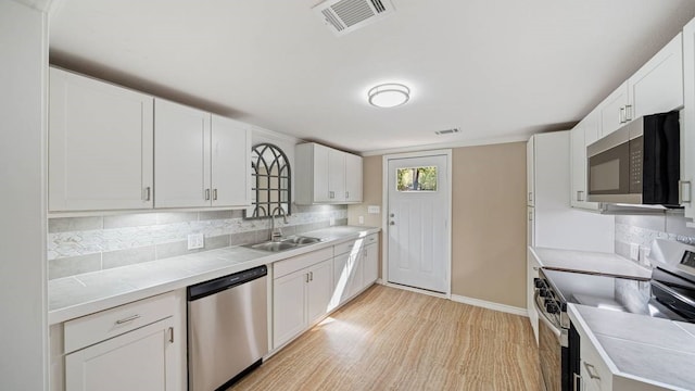 kitchen with white cabinetry, tasteful backsplash, stainless steel appliances, and sink