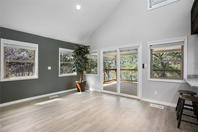 unfurnished room featuring light hardwood / wood-style flooring, high vaulted ceiling, and plenty of natural light