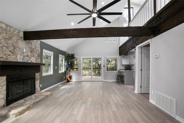 unfurnished living room with high vaulted ceiling, light wood-type flooring, and a healthy amount of sunlight