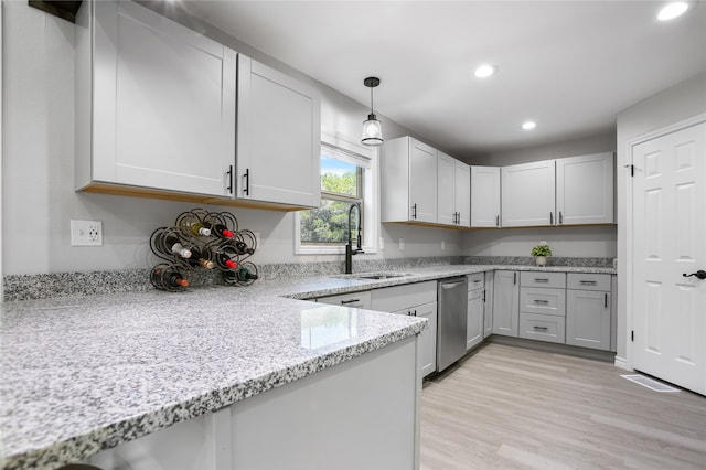 kitchen featuring sink, light stone countertops, pendant lighting, light wood-type flooring, and stainless steel dishwasher