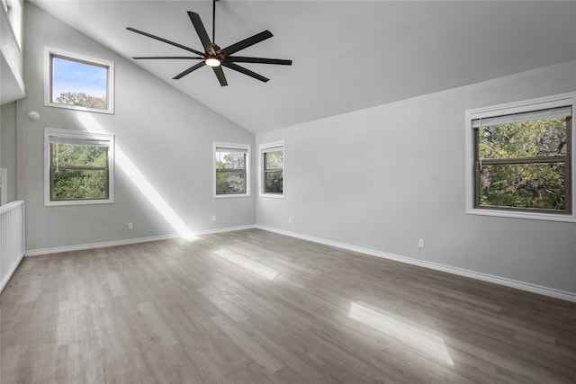 spare room with high vaulted ceiling, a wealth of natural light, and hardwood / wood-style floors