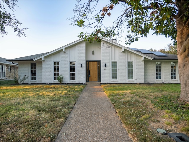 view of front of house with a front lawn and solar panels