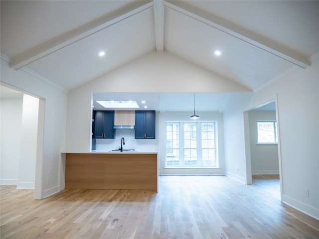 kitchen featuring kitchen peninsula, light hardwood / wood-style flooring, pendant lighting, lofted ceiling with beams, and sink