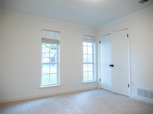 empty room featuring light carpet, ornamental molding, and a healthy amount of sunlight