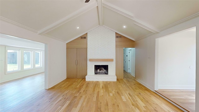 unfurnished living room with light hardwood / wood-style floors, crown molding, vaulted ceiling with beams, and a brick fireplace