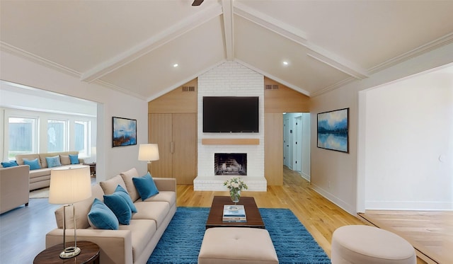 living room with a fireplace, ornamental molding, lofted ceiling with beams, and light wood-type flooring