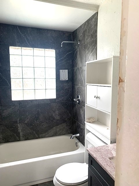 full bathroom with toilet, tiled shower / bath combo, and vanity