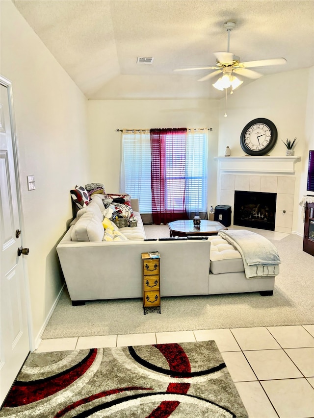 tiled living room featuring a tiled fireplace, a textured ceiling, lofted ceiling, and ceiling fan