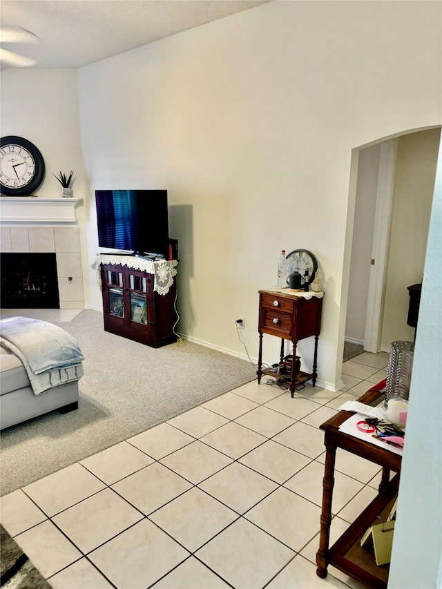 carpeted living room featuring a tile fireplace and ceiling fan