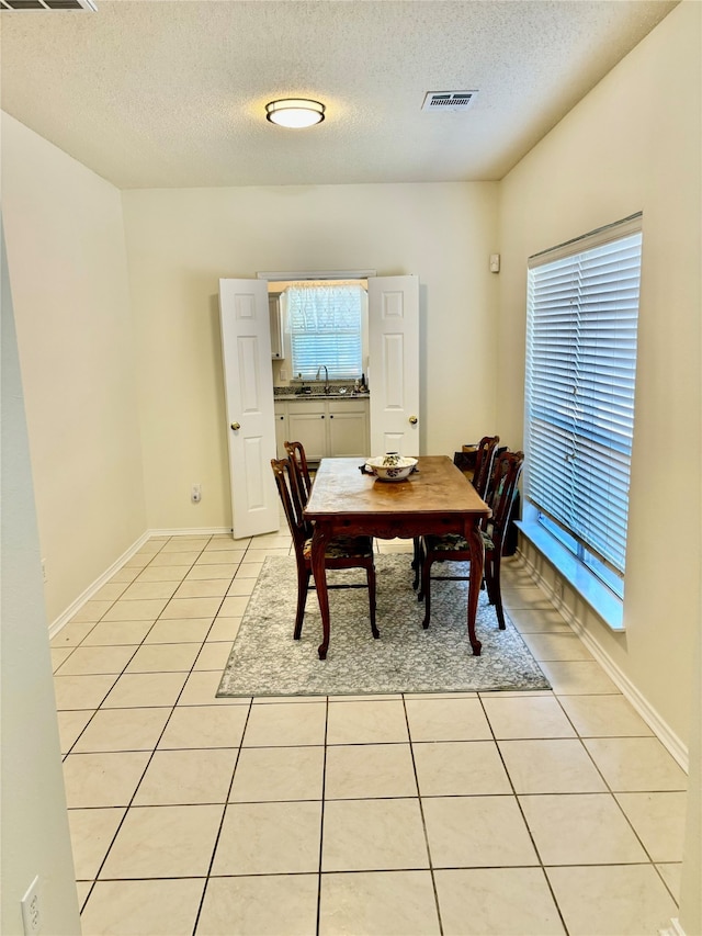 dining space with sink, light tile patterned flooring, and a textured ceiling