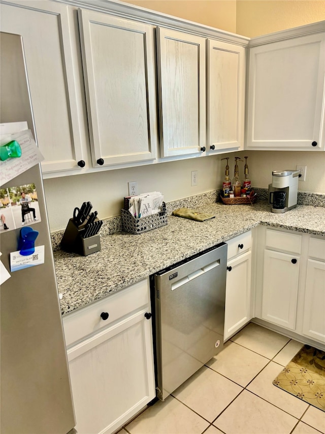 kitchen with appliances with stainless steel finishes, white cabinets, light stone counters, and light tile patterned floors