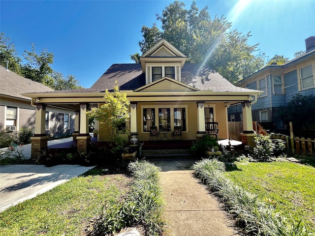 view of front facade with covered porch, a front yard, and cooling unit