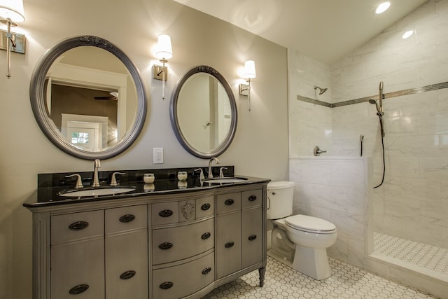 bathroom with lofted ceiling, a tile shower, toilet, vanity, and tile patterned floors