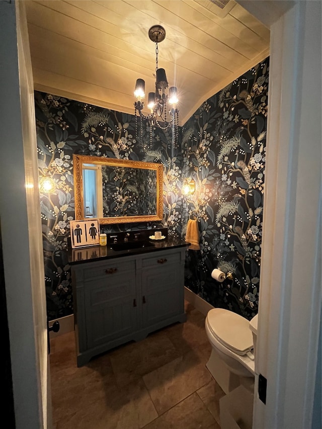 bathroom with an inviting chandelier, wooden ceiling, toilet, vanity, and tile patterned floors