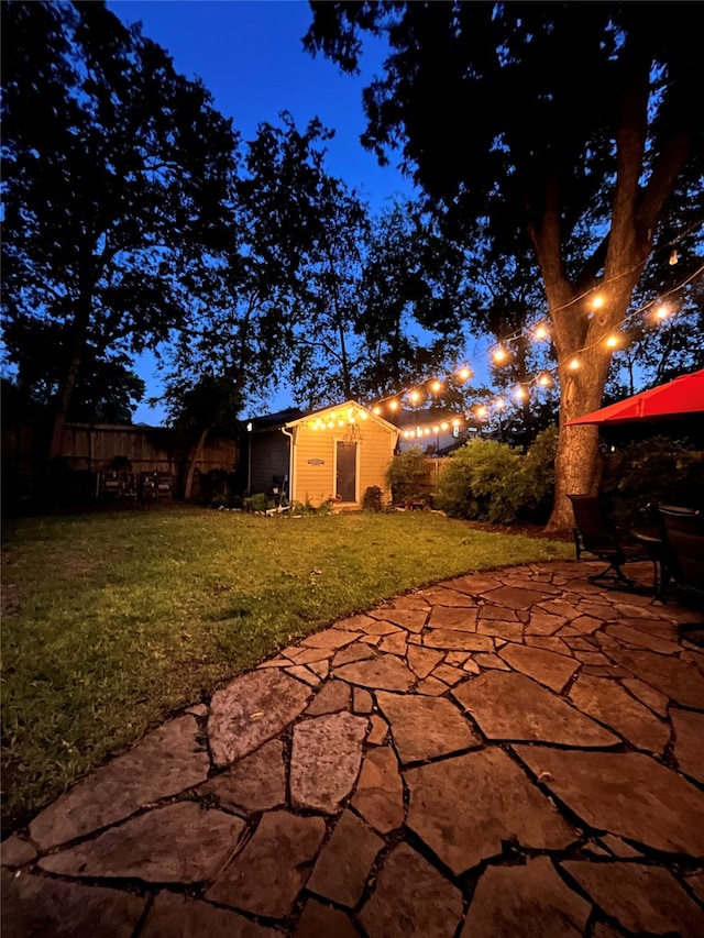 patio at twilight with a yard and a storage shed