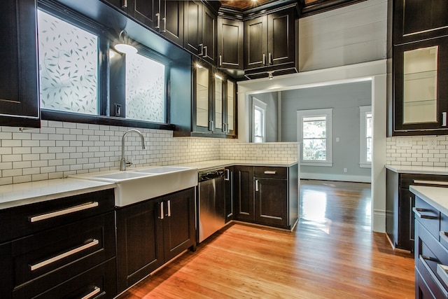 kitchen with sink, dishwasher, light wood-type flooring, and tasteful backsplash