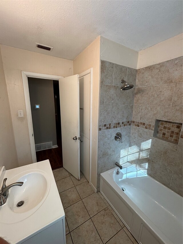 bathroom with vanity, tile patterned floors, a textured ceiling, and tiled shower / bath